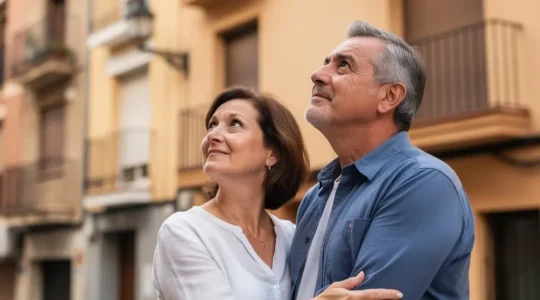 Pareja española evaluando fachada de edificio residencial para tasación inmobiliaria